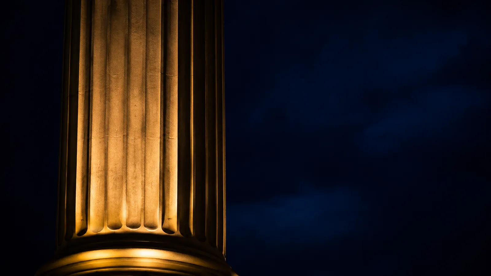 Floodlight washing up a fluted stone column after dark